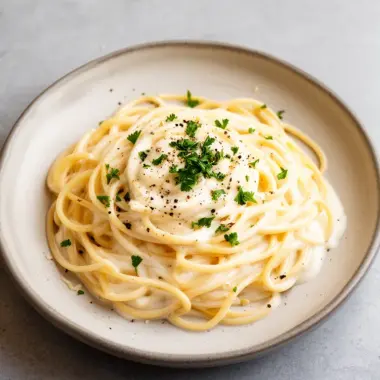 Creamy homemade Alfredo sauce served with pasta on a plate.