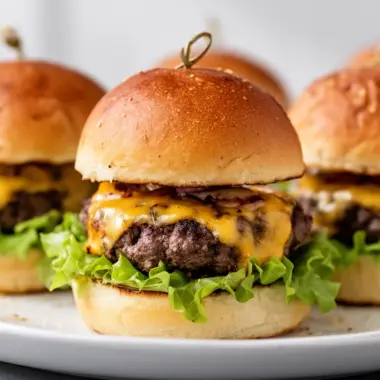 Juicy cheeseburger sliders served on a platter with condiments.